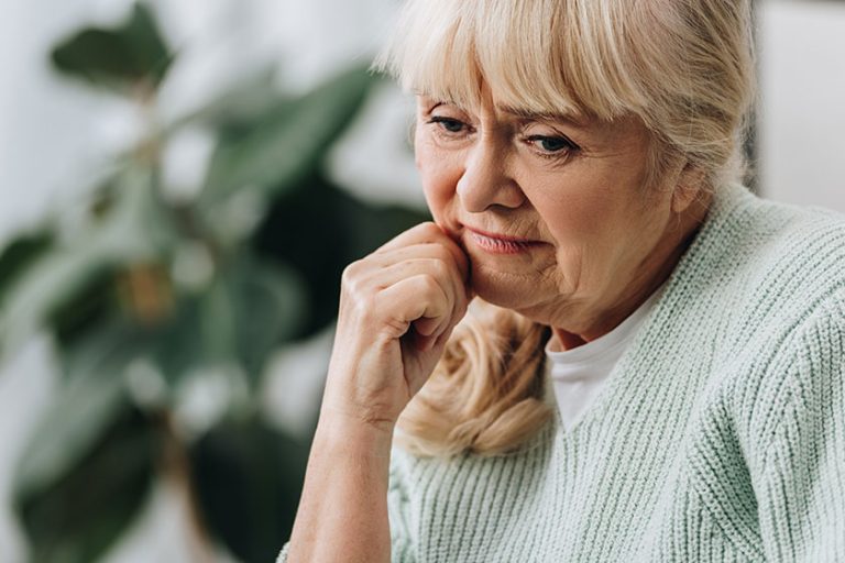 pensive blonde senior woman living room