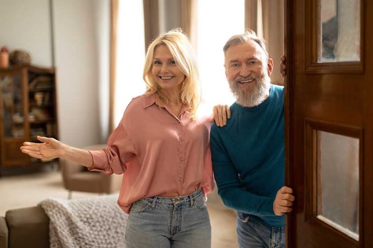 cheerful senior spouses opening door new apartment welcoming you smiling