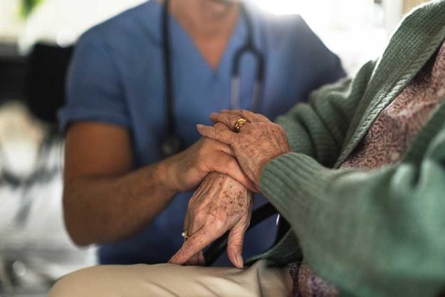 close caregiverr holding hands his senior client concept healthcare relationships