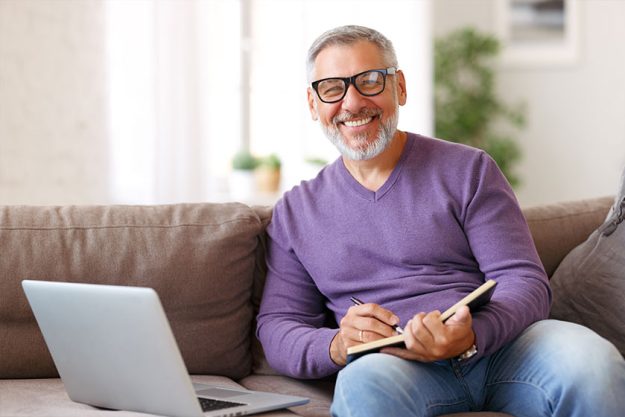 handsome positive senior man wearing glasses working remotely while sitting handsome positive senior man wearing glasses working remotely while sitting