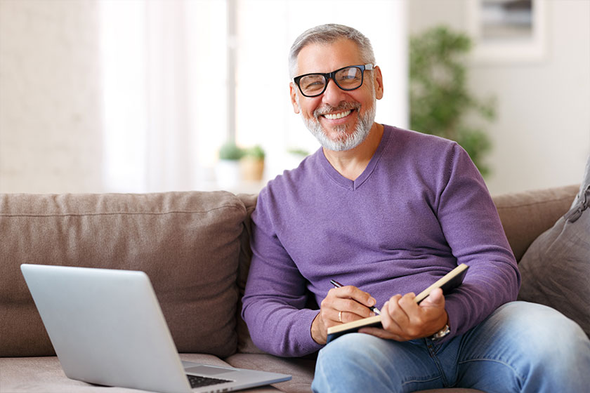 handsome positive senior man wearing glasses working remotely while sitting handsome positive senior man wearing glasses working remotely while sitting