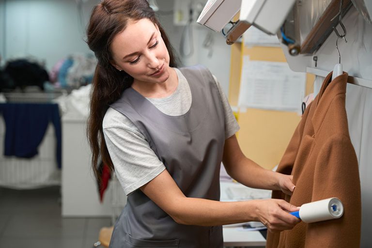 laundry service woman doing post treatment garment removing lints sticky