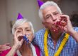 Close up portrait of senior couple blowing party horn at home