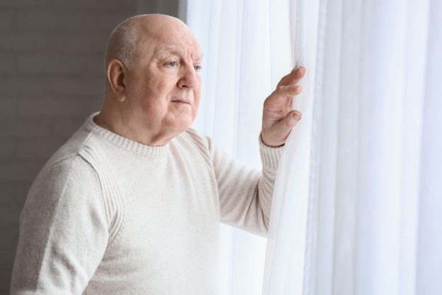 Elderly man suffering from mental disability near window at home