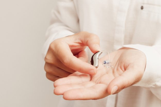 Hearing aids. Young Female Doctor Showing Hearing Aid To Patient