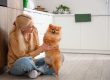 Mature woman with Pomeranian dog in kitchen