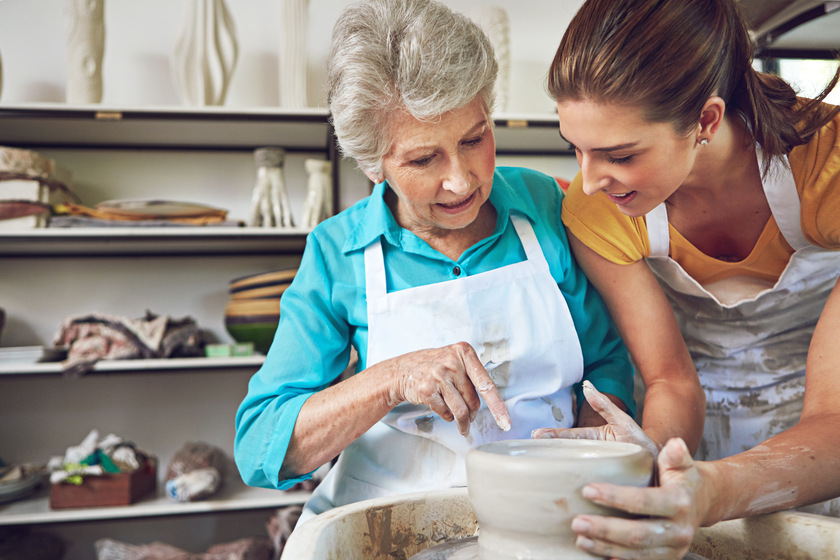 Passing on her pottery skills to Mom. a senior woman making a ceramic pot at a pottery class.
