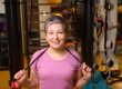 Portrait of middle aged smiling woman wearing sportswear with skipping rope
