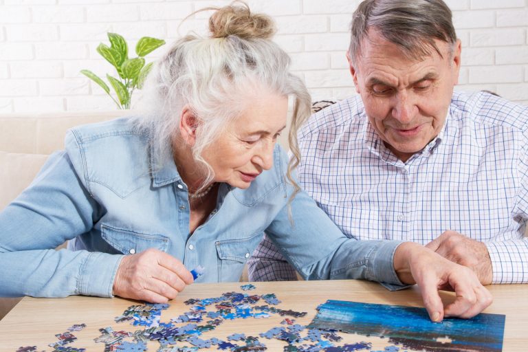 Senior couple solving jigsaw puzzle together at home