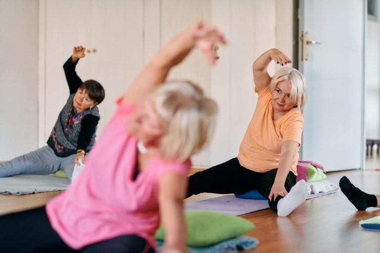 Senior Women Embrace Wellness: Yoga and Stretching in a Sunlit Space