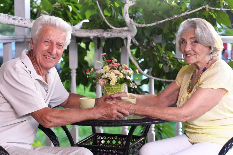Elderly couple sitting at the table in the summer at the country house