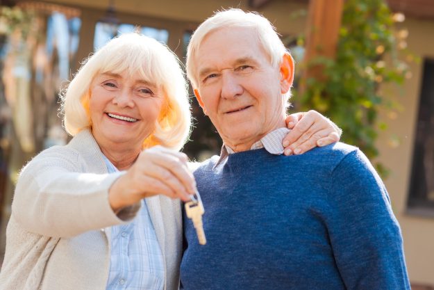 Happy seniors. Happy senior couple bonding to each other and smiling while woman holding keys in her hand Happy seniors. Happy senior couple bonding to each other and smiling while woman holding keys in her hand