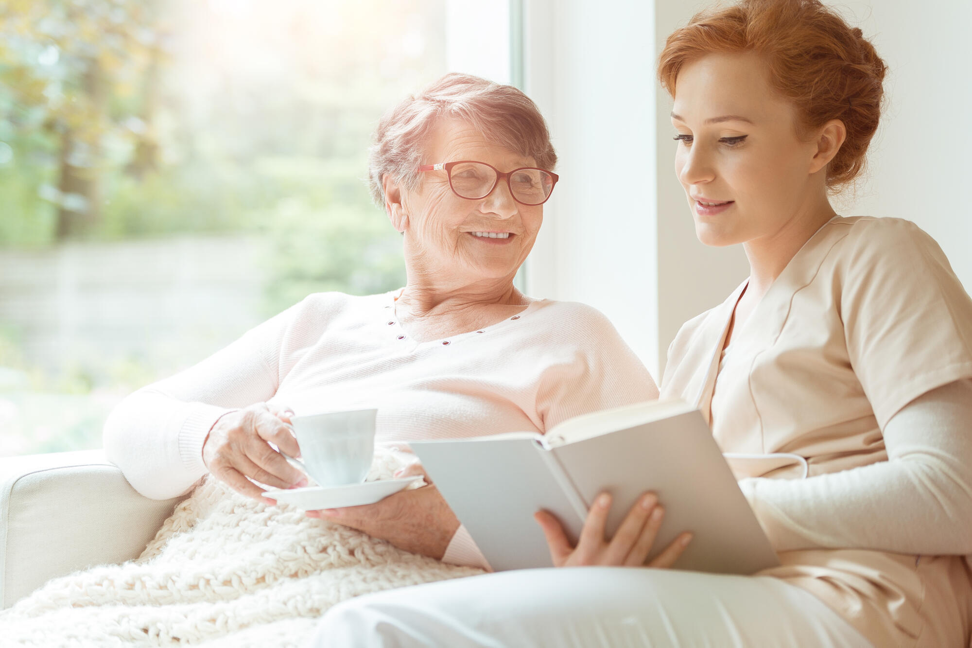 Woman,Reading,A,Book,While,Sitting,With,Happy,Grandmother,Drinking Woman,Reading,A,Book,While,Sitting,With,Happy,Grandmother,Drinking