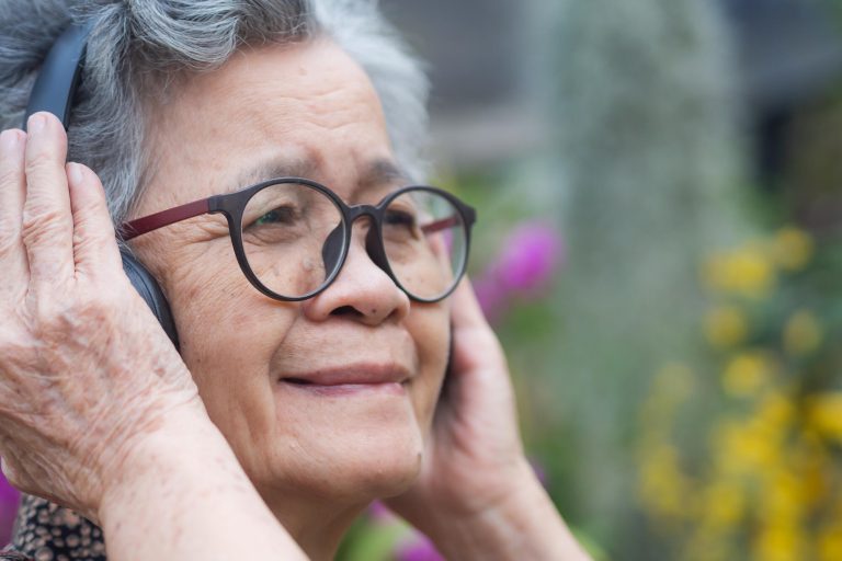Cheerful senior woman with short gray hair, wearing glasses, smi