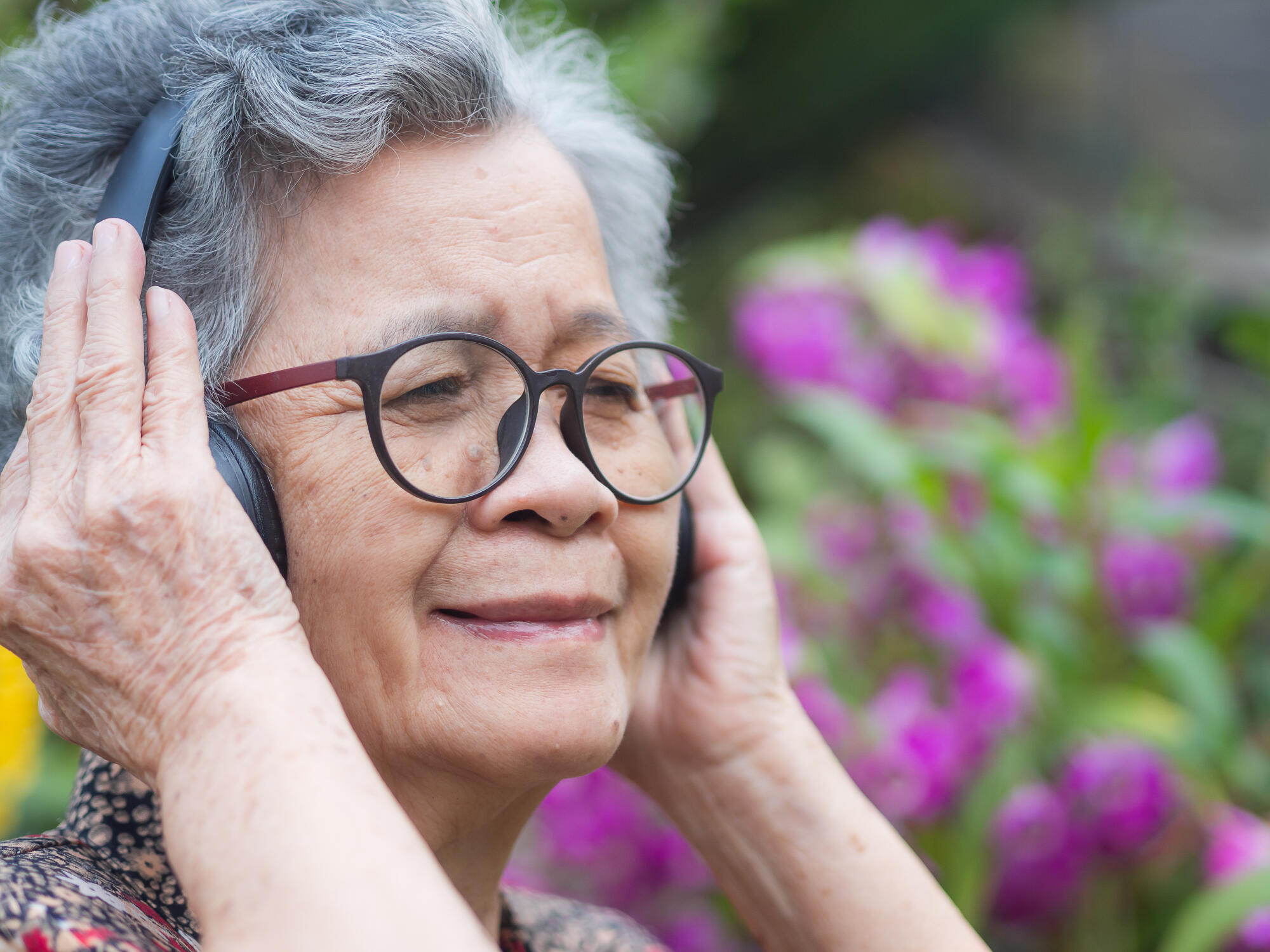 Cheerful senior woman with short gray hair, wearing glasses, smi