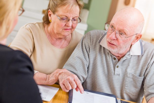 Senior Adult Couple Going Over Documents in Their Home with Agent At Signing.