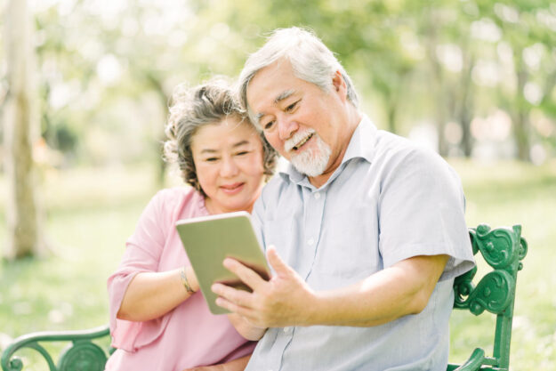Happy senior Asian couple using tablet