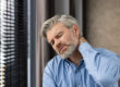 Middle aged businessman experiencing neck pain in office setting
