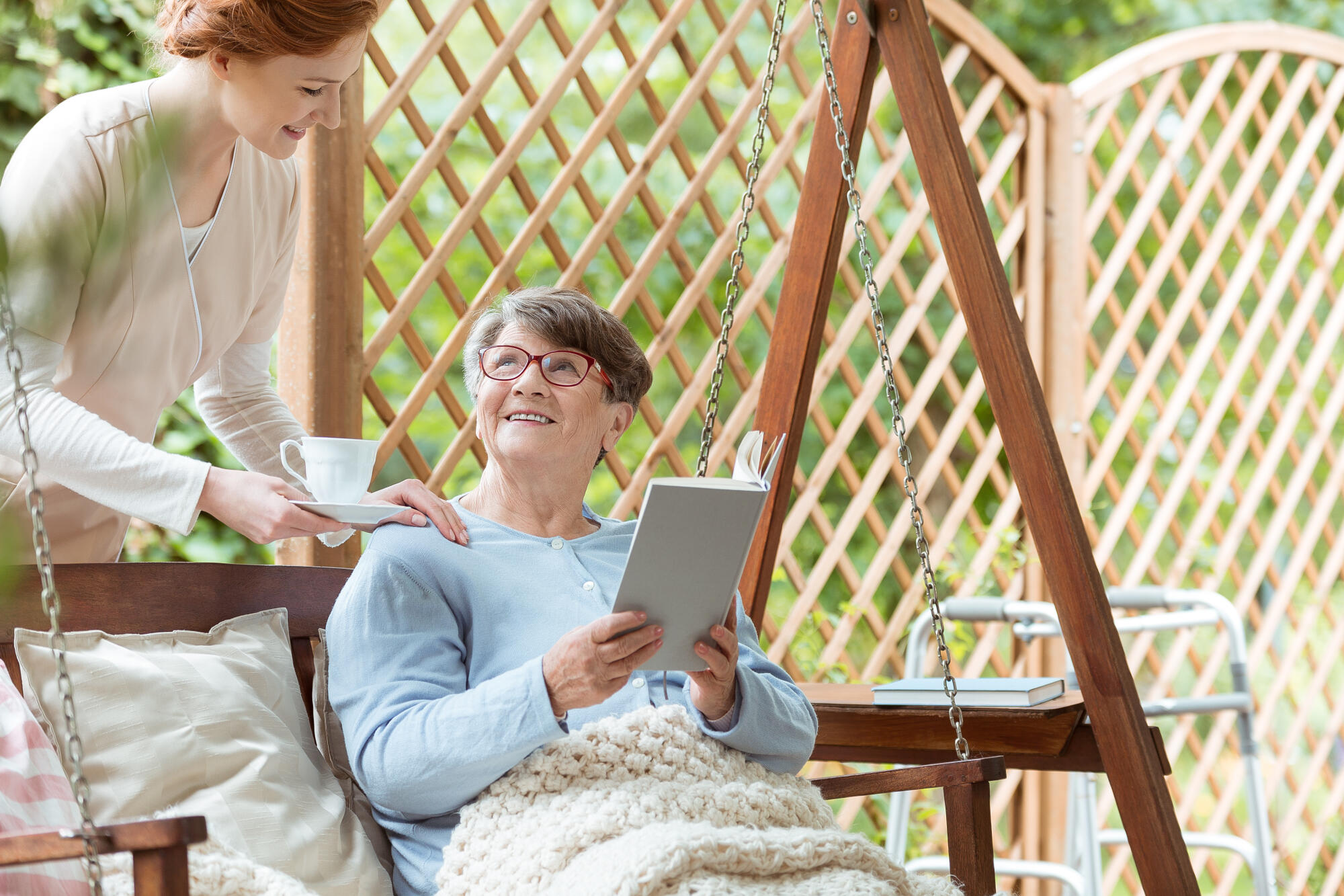 Elder,Woman,Reading,A,Book,While,Sitting,On,Hanging,Bench