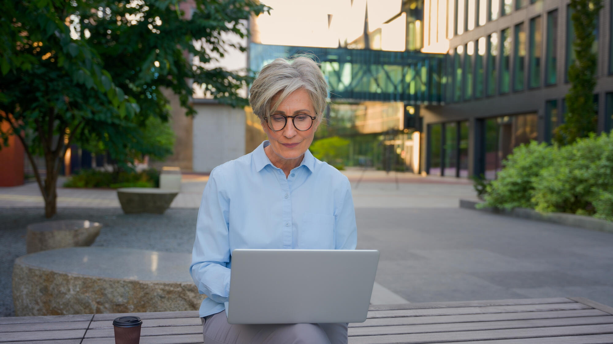 Mature woman working online typing email business chat in internet using laptop pc computer senior old businesswoman in city modern urban street downtown female entrepreneur work with project outside
