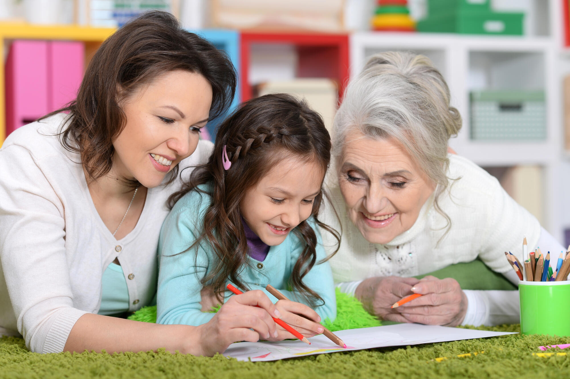 Portrait of cute girl grawing with mom and grandma
