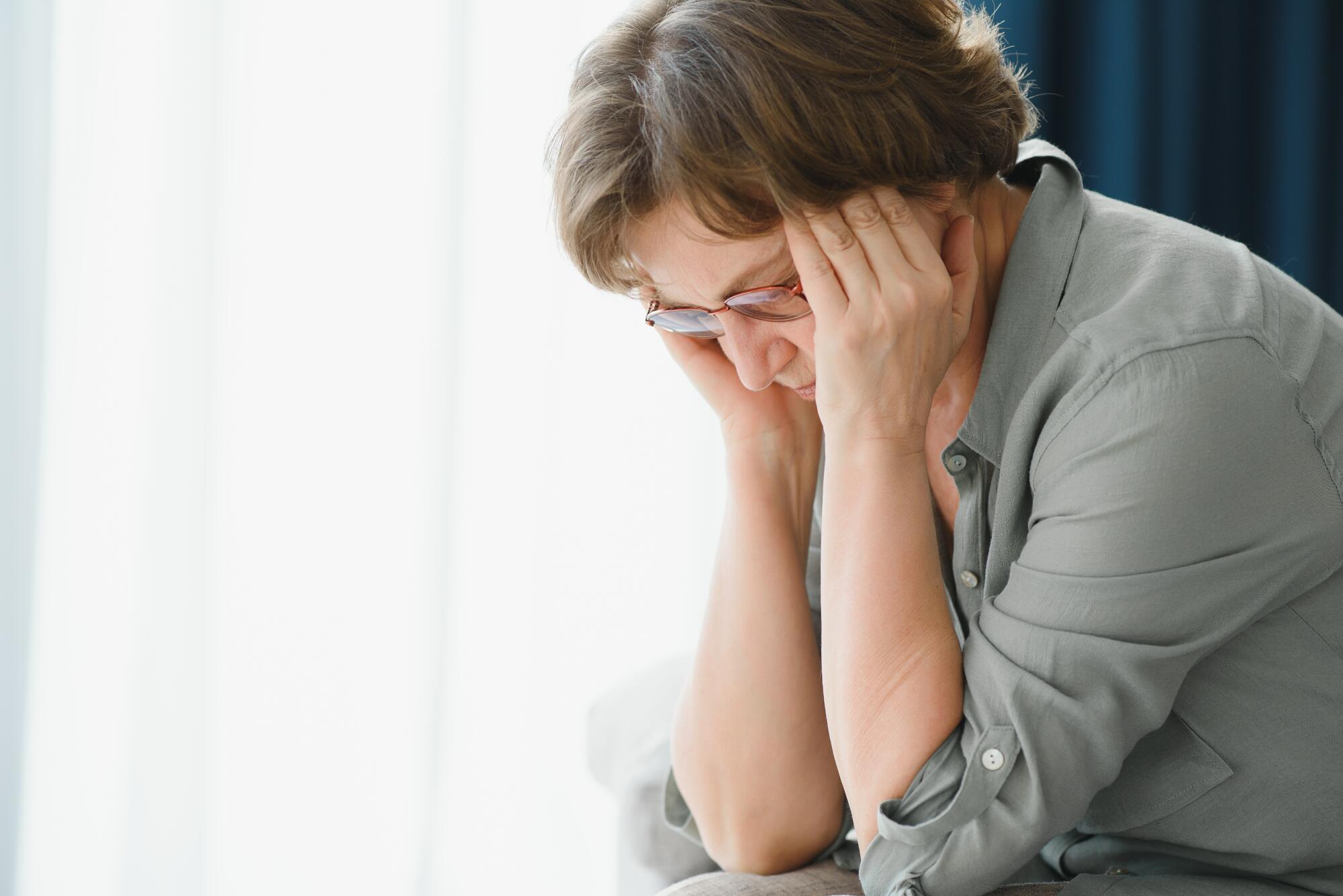 health care, pain, stress, age and people concept face of senior woman suffering from headache