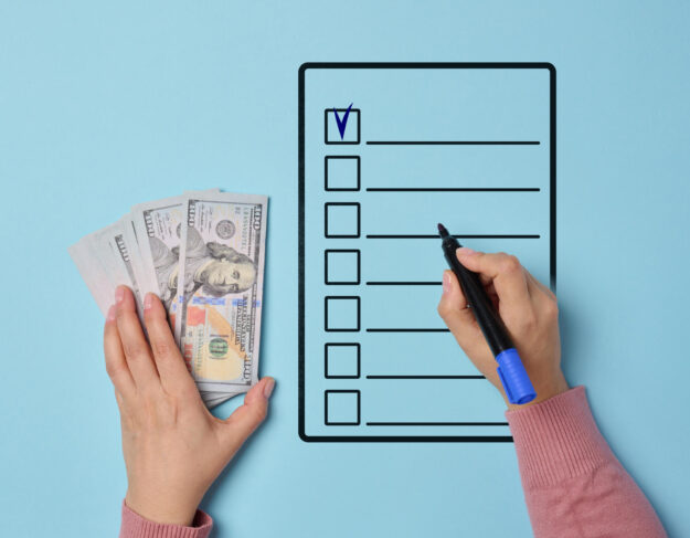 A woman's hand holding a stack of American dollars and filling o