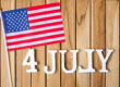 Fourth of July text and United States of America flag on wooden