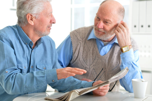 Two elderly men drinking coffee and reading newspaper Two elderly men drinking coffee and reading newspaper