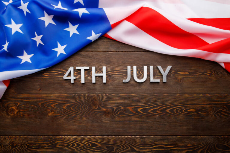the words 4th july and crumpled usa flag on flat textured wooden surface background
