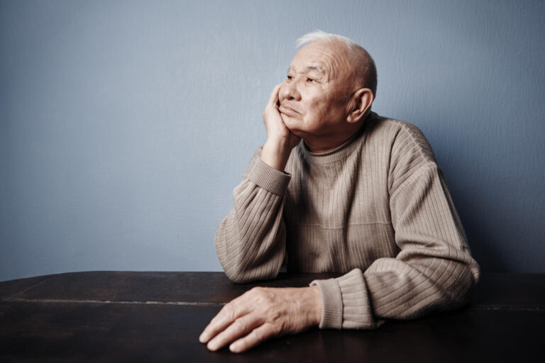 Pensive and thoughtful senior man sitting at the table