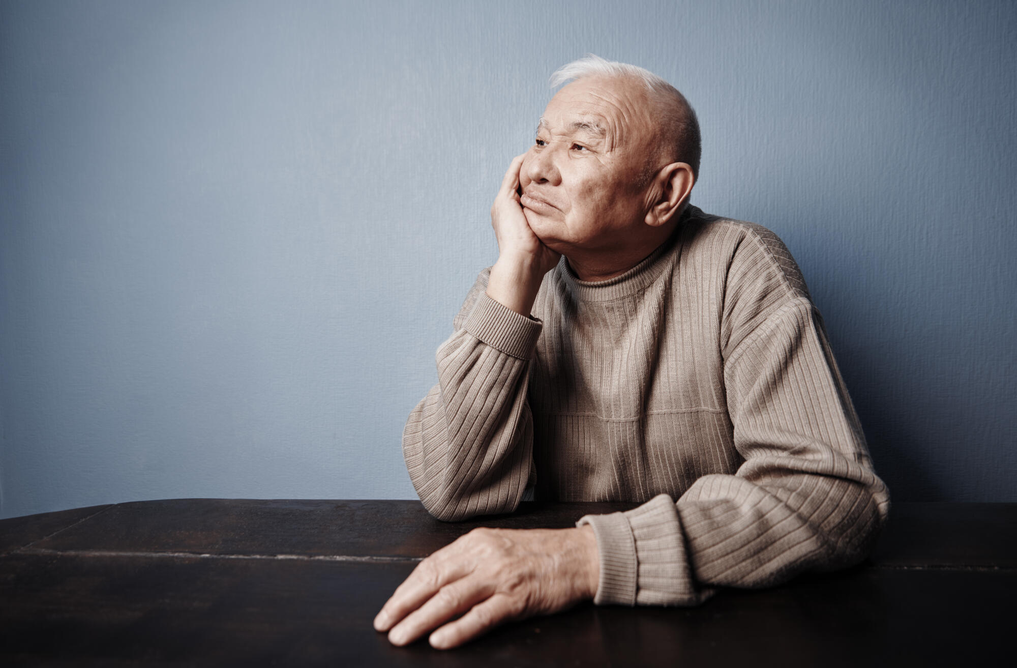 Pensive and thoughtful senior man sitting at the table