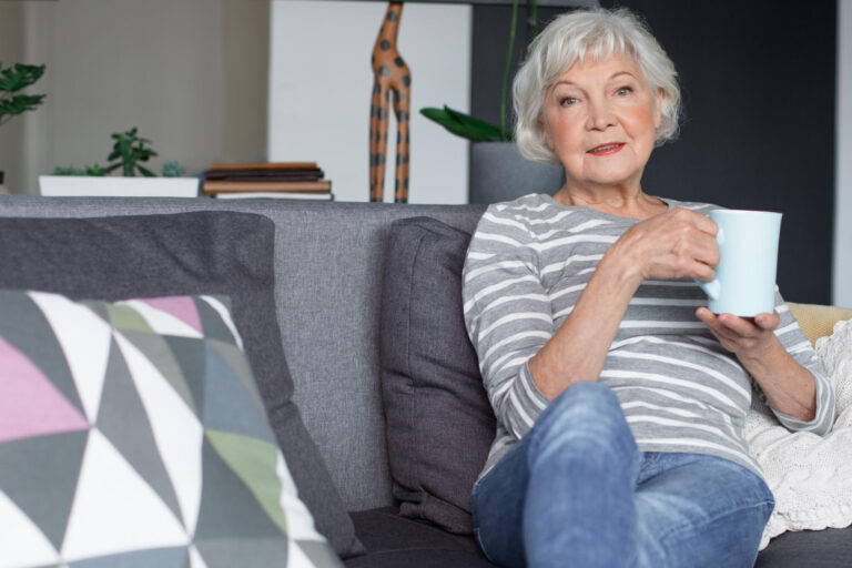 Portrait,Of,Old,Mature,Lady,Sitting,On,Couch,And,Smiling.
