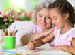 Portrait of a cute little girl drawing with her grandmother
