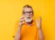 Portrait of happy senior man wearing glasses yellow shirt posing unaltered