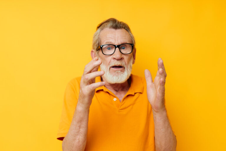 Portrait of happy senior man wearing glasses yellow shirt posing unaltered