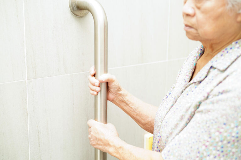Asian elderly old woman patient use toilet support rail in bathr