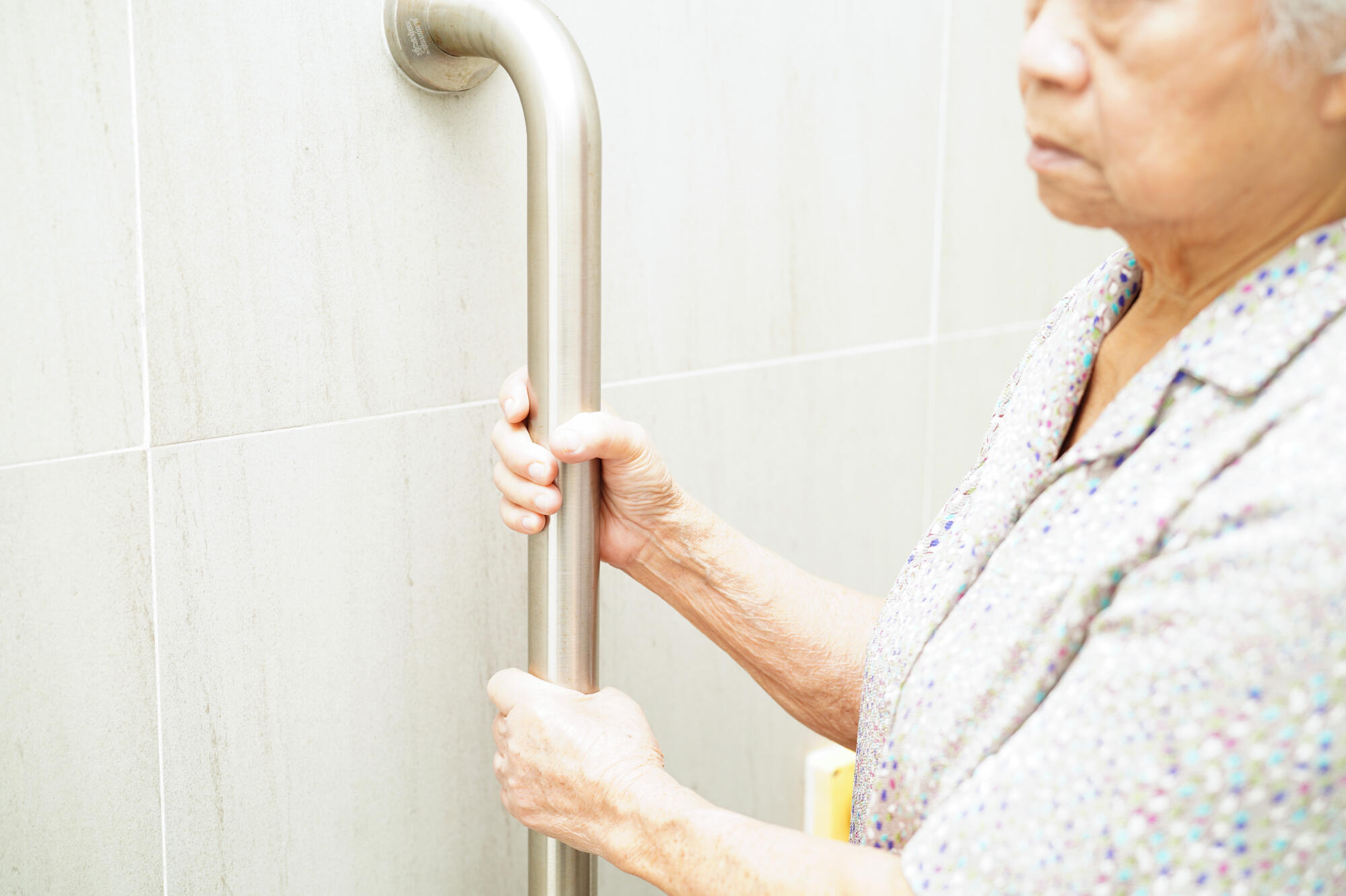 Asian elderly old woman patient use toilet support rail in bathr