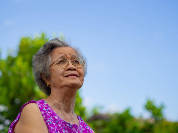 Portrait of an elderly Asian woman wearing glasses and looking u
