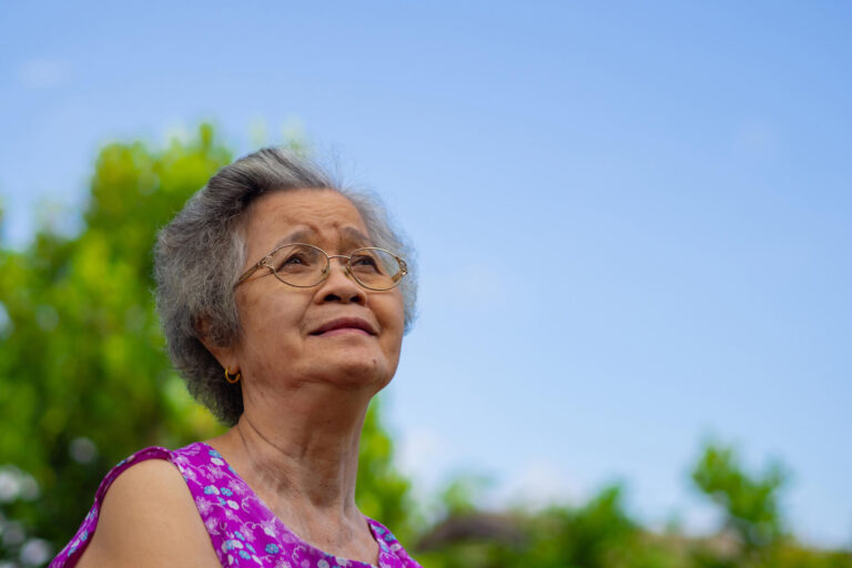Portrait of an elderly Asian woman wearing glasses and looking u