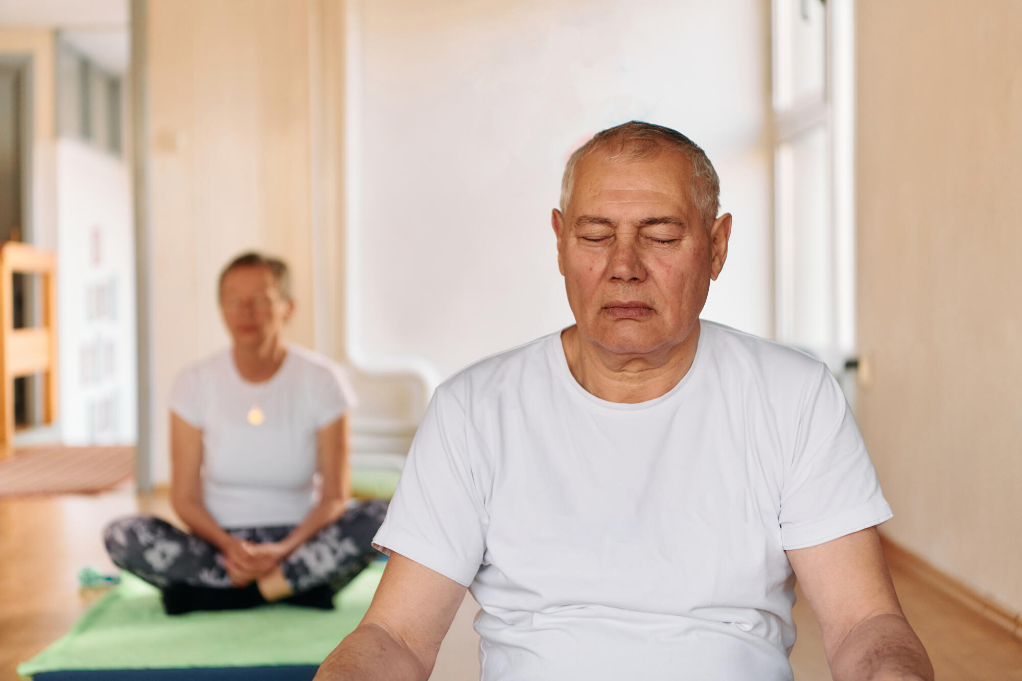 Close up of a senior man deeply focused on meditation and relaxation during a yoga practice.