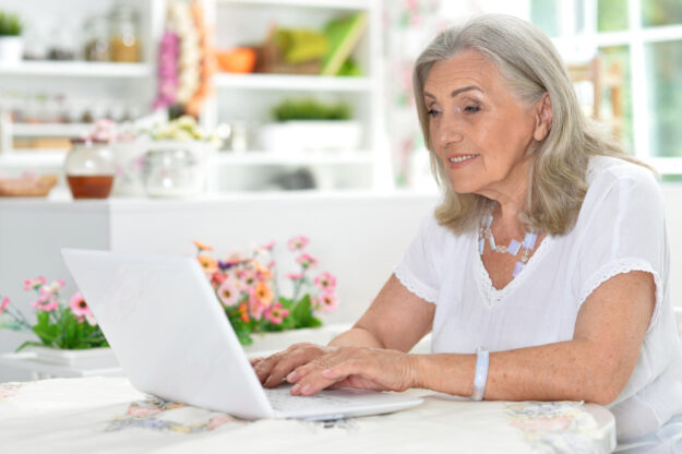 Cute nice senior woman using laptop at home Cute nice senior woman using laptop at home