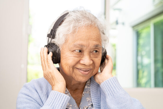 Asian senior woman listen to music with headphone smile and enjo Asian senior woman listen to music with headphone smile and enjo
